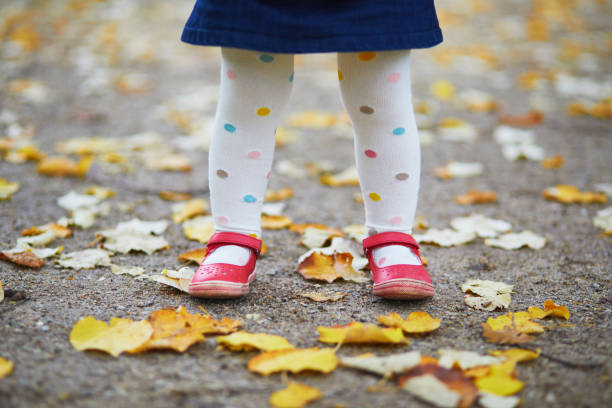 Toddler girl in red shoes and polka dot pantihose standing on fallen leaves in a fall day Toddler girl in red shoes and polka dot pantihose standing on fallen leaves in a fall day. Child enjoying autumn day in park. Stylish and beautiful clothes for kids pantyhose stock pictures, royalty-free photos & images