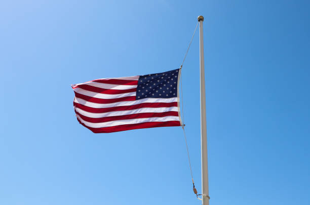 istock American Flag Waving on Pole in Blue Sky 1190627435