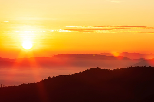 Glowing sunrise shines over mountain range.