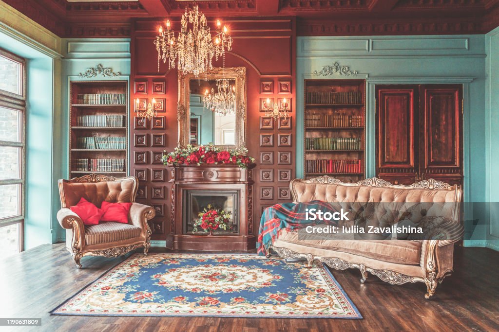 Luxury classic interior of home library. Sitting room with bookshelf, books, arm chair, sofa and fireplace Luxury classic interior of home library. Sitting room with bookshelf, books, arm chair, sofa and fireplace. Clean and modern decoration with elegant furniture. Education read study wisdom concept Old-fashioned Stock Photo