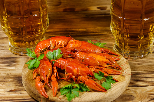 Boiled crayfish and two mugs of beer on a wooden table