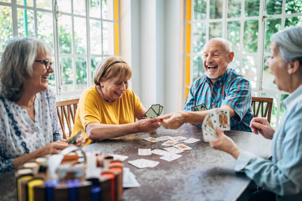 alte menschen haben spaß beim kartenspielen im pflegeheim - senioren stock-fotos und bilder