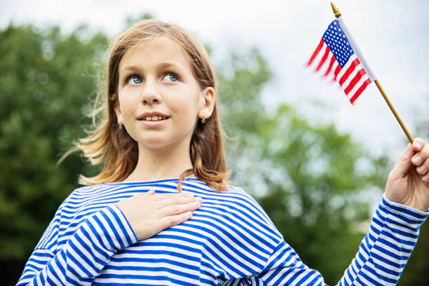 Fourth Of July Celebration young patriot girl, holding an American flag national anthem stock pictures, royalty-free photos & images