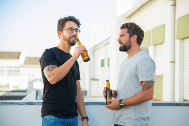 istock Two male friends enjoying party, chatting, drinking beer 1190633920