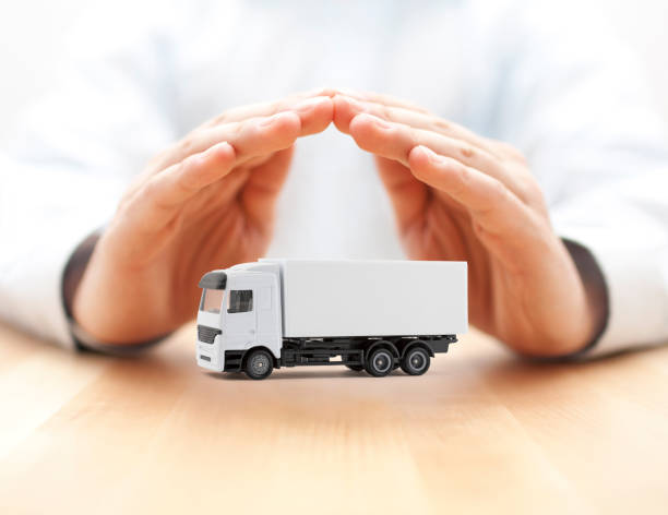 istock Cargo delivery truck protected by hands over wooden background 1190638698