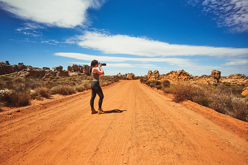 Shot of a young woman taking photos in a rural landscape