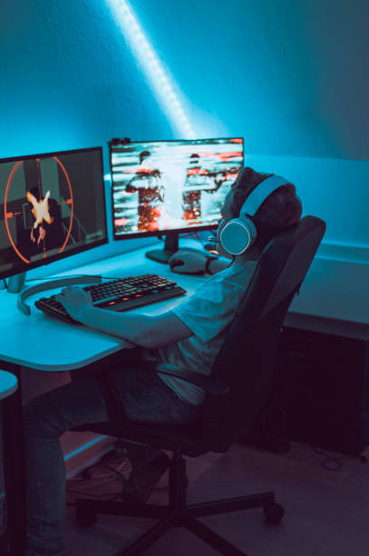istock Boy plays video game online and sits in front of two big computer monitors 1190641101