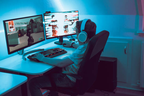 istock Boy plays video game online and sits in front of two big computer monitors 1190641252