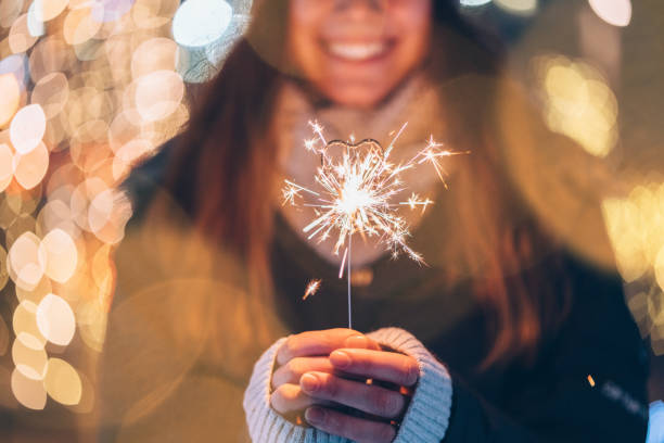 Girl holding burning sparkler during Christmas Happy woman making a Christmas wish outside glittering burning stock pictures, royalty-free photos & images