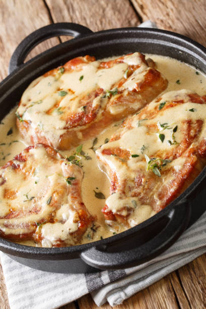 istock Cooked pork chops in creamy wine sauce with thyme close-up in a pan. vertical 1190643276