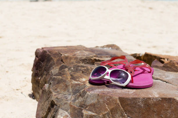 岩の上にメガネとピンクの靴で夏休み。 - coral break ストックフォトと画像