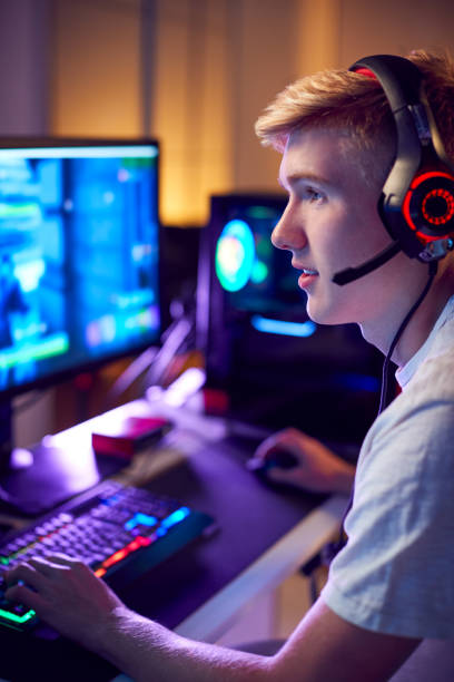 istock Teenage Boy Wearing Headset Gaming At Home Using Dual Computer Screens 1190647592