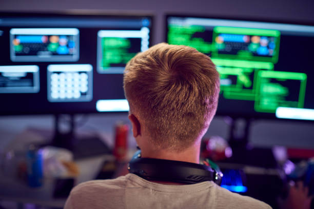 istock Male Teenage Hacker Sitting In Front Of Computer Screens Bypassing Cyber Security 1190647708