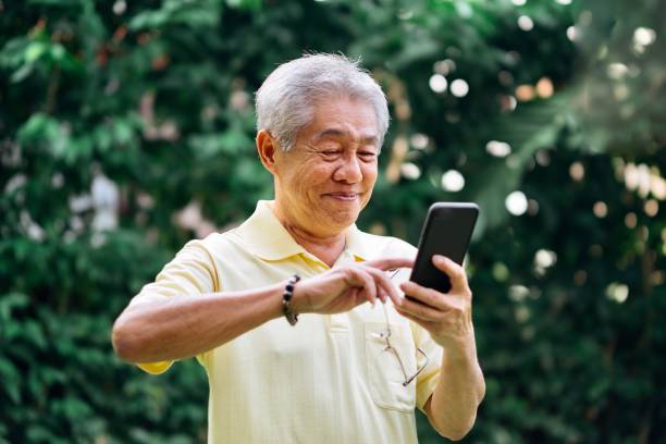 verticale de l'homme chinois aîné utilisant le smartphone - chinese ethnicity aging process family asian ethnicity photos et images de collection