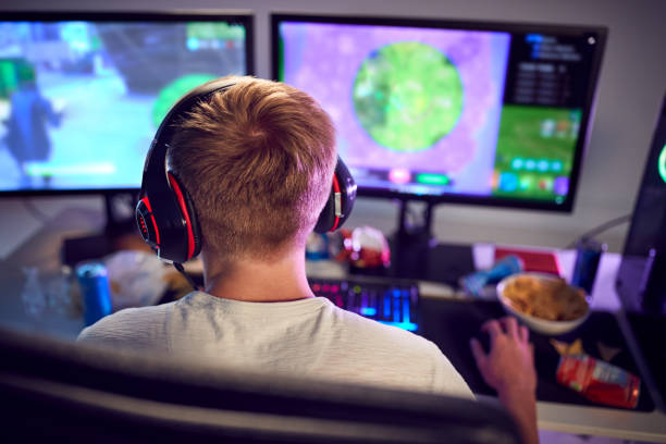 istock Teenage Boy Wearing Headset Gaming At Home Using Dual Computer Screens 1190647904