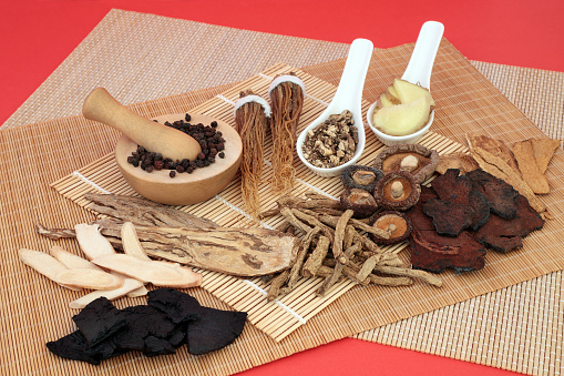 Chinese herbs used as a tonic in traditional herbal medicine on bamboo and red background.