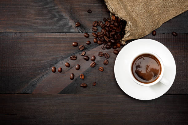 istock Coffee in a white cup and coffee beans on the table. Top view. Dark background. 1190649997