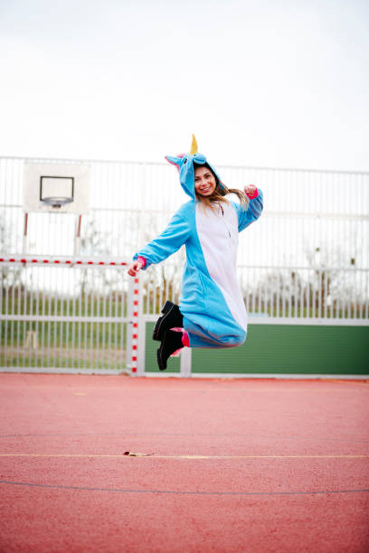 beautiful woman wearing turquoise unicorn onesie in urban environment - onesie imagens e fotografias de stock