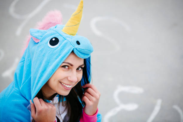 beautiful woman wearing turquoise unicorn onesie in urban environment - onesie imagens e fotografias de stock