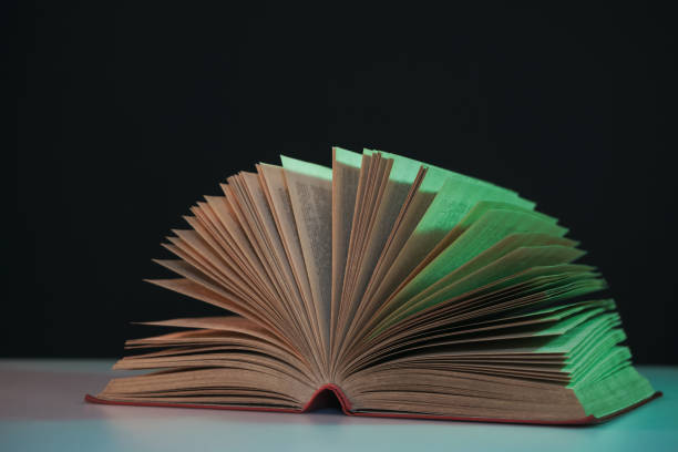 istock Beautiful open book pages in the color neon light on a table and night background. 1190656237