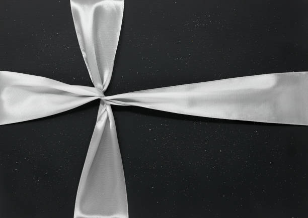Silver ribbon tied around a dark glittery background, minimal Christmas gift concept
