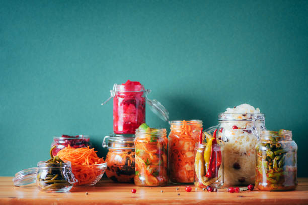 Assortment of various fermented and marinated food over wooden background, copy space. Fermented vegetables, sauerkraut, pepper, garlic, beetroot, korean carrot, cucumber kimchi in glass jars. Assortment of various fermented and marinated food over wooden background, copy space. Fermented vegetables, sauerkraut, pepper, garlic, beetroot, korean carrot, cucumber kimchi in glass jars hot mix plant stock pictures, royalty-free photos & images