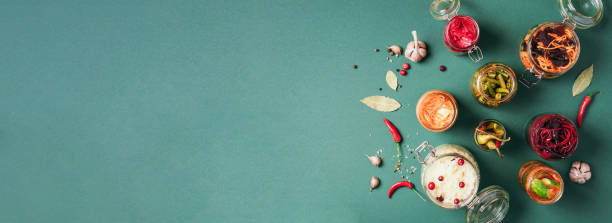 istock Assortment of various fermented and marinated food over green background, copy space. Top view. Banner. Fermented vegetables, sauerkraut, pepper, garlic, beetroot, korean carrot, cucumber kimchi in glass jars. 1190656709