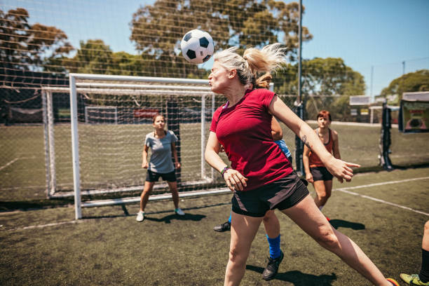 decidida jugadora de fútbol femenina jugando con la cabeza durante el partido - head shoot fotografías e imágenes de stock