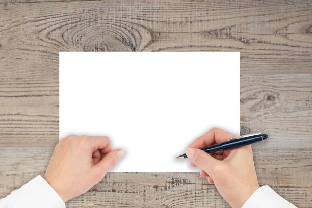 istock A hand is writing on a paper on a wooden table. Make notes, make plans, write, draw. Top view with copy space. 1190659391