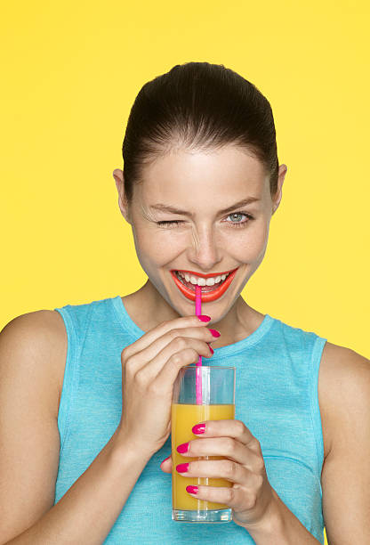 young female drinking and winking - drinking straw drinking juice women fotografías e imágenes de stock