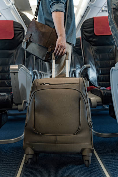 istock Man is holding bag and suitcase in airplane 1190663471