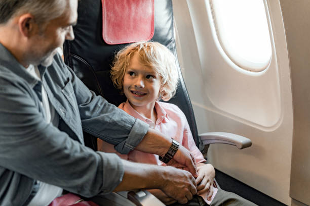istock Smiling man is looking on little son in airplane 1190663540