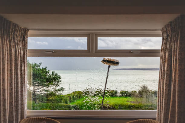 istock A double glazed picture window with small top light opening windows being cleaned with an extension brush and pure water. Some motion blur showing the movement of the brush. There is a sea view. 1190664734