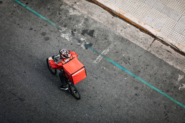 Delivering Food on Bicycle In City A young man working for a food delivery service in a sustainable way, riding bike sports helmet photos stock pictures, royalty-free photos & images