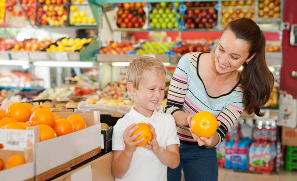 istock boy with his mom choosing oranges 1190669786