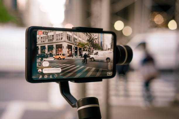 homem que faz o vídeo vivo com telefone com estabilizador em ny - photo messaging telephone photographing camera - fotografias e filmes do acervo