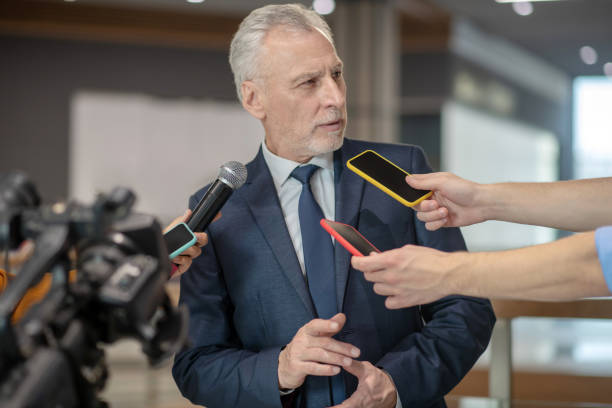 istock Grey-haired bearded man looking unsatisfied at the press conference 1190684910