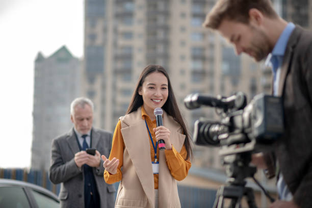 istock Young cute female reporter talking to a videocamera 1190684934