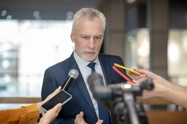 Photo of Grey-haired bearded man looking concentrated at the press conference