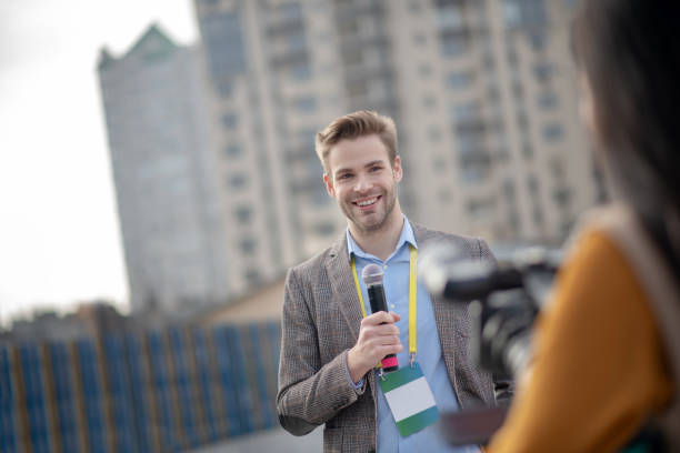 istock Young bearded reporter holding a microphone in his hand 1190684947
