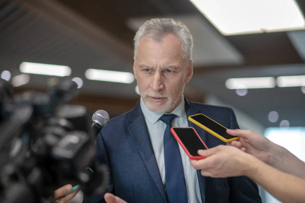 istock Grey-haired bearded man looking serious at the press conference 1190684983