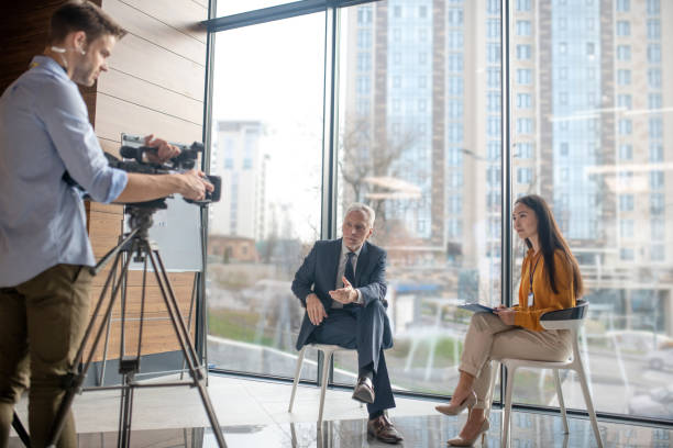istock Asian female reporter siting in the studio talking to a greay-haired man 1190685177
