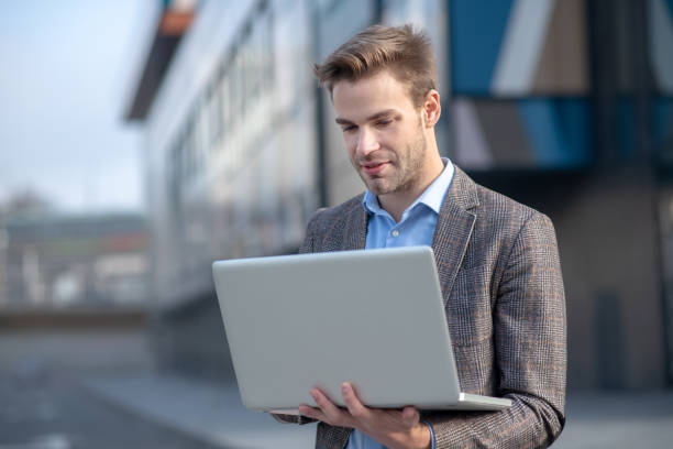 istock Young man in a blue shirt holding a laptop 1190685343