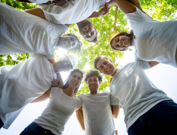 istock Mixed aged volunteer group all in a huddle hugging each other smiling at camera 1190691987