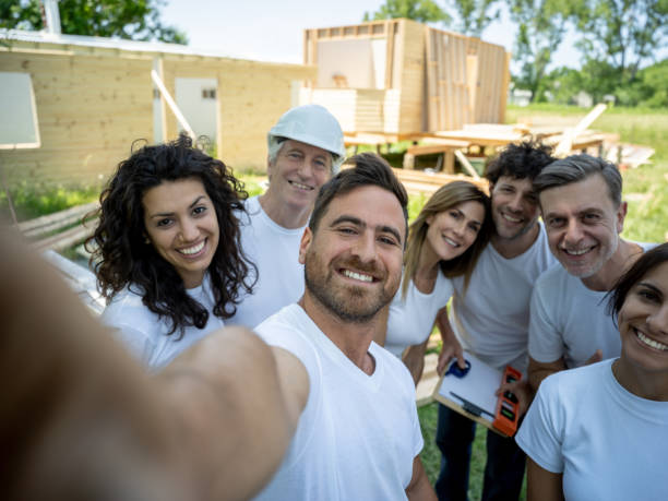 Mixed aged group of volunteers at a construction site taking a selfie all smiling at camera