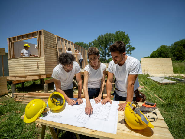 istock Female leader instructing male volunteers while pointing at a blueprint on construction site 1190692011