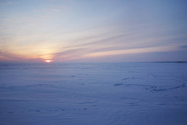 Snowy field and snow kiteboarders against the backdrop of a beautiful sunset.