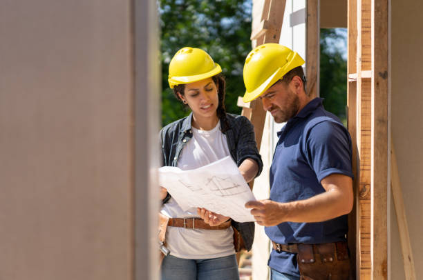 istock Female architect discussing something with contractor while looking at a blueprint at a construction project 1190692725