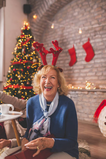 istock Senior woman opening Christmas present and laughing 1190697828