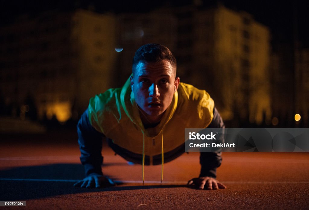Strong man exercising at night Young strong man exercising at night in sports clothes Dark Stock Photo